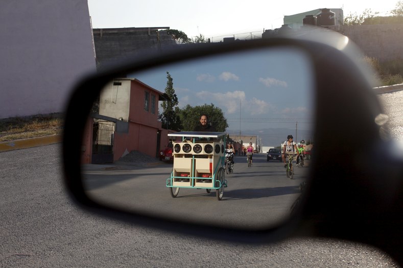 Chapa is reflected in a side mirror as he pedals his Cinecleta, Moviebike, through the streets of Saltillo