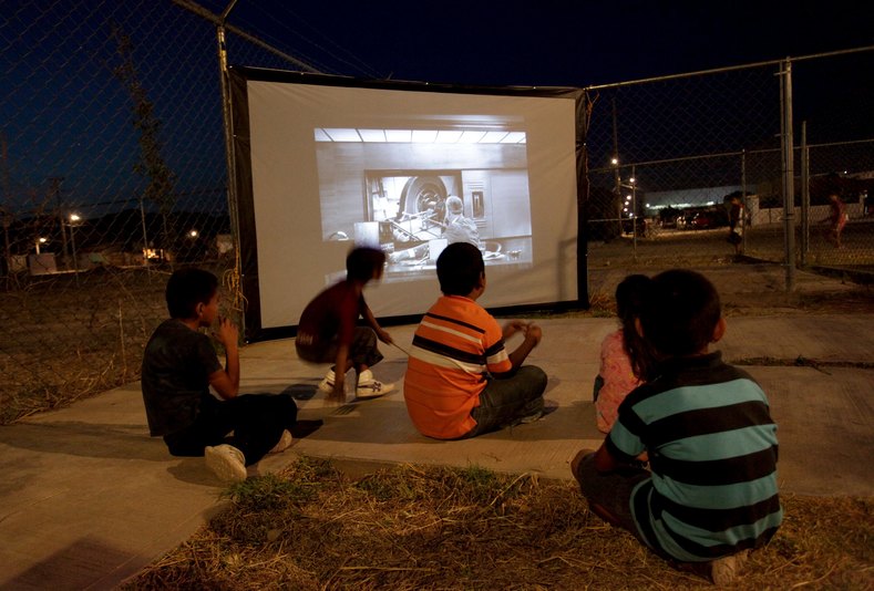 Children watch a movie projected by the Cinecleta, Moviebike, at a park in Saltillo