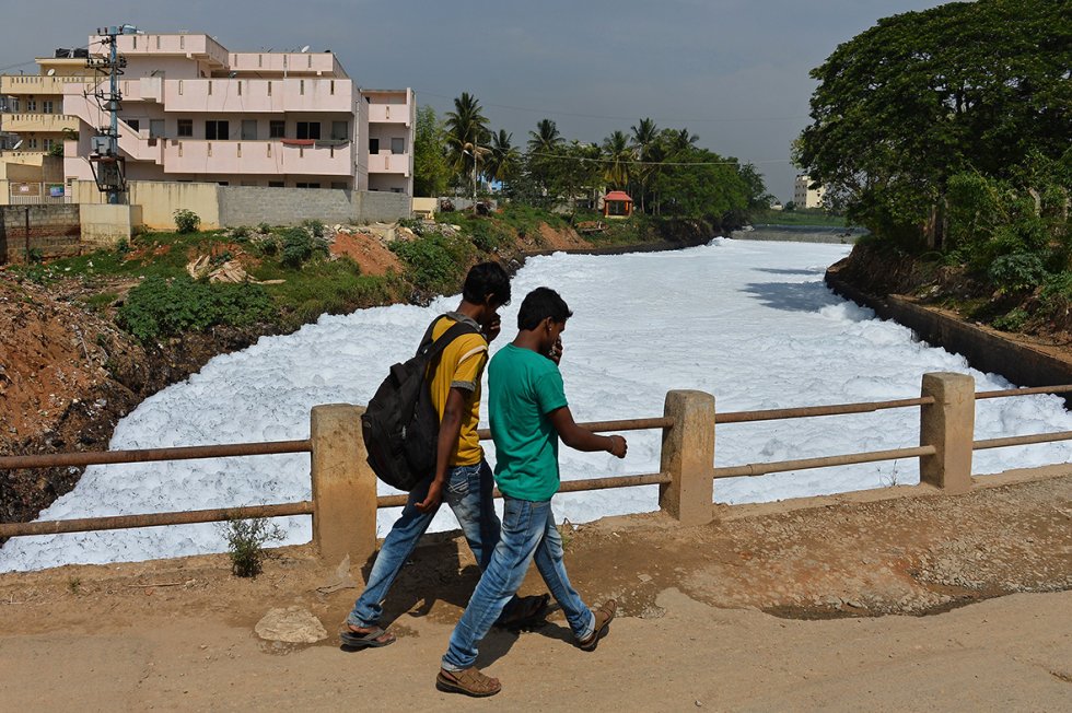 Pedestrians cover their noses as they cross a bridge over a polluted canal in east Bangalore