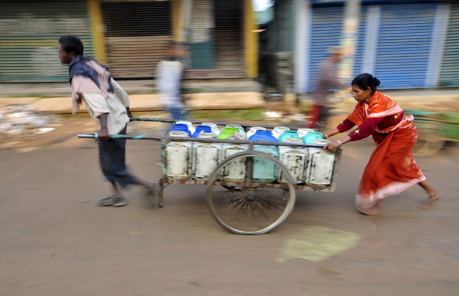 ndian labourers transport canisters of drinking water to distribute to food stalls in Agartala