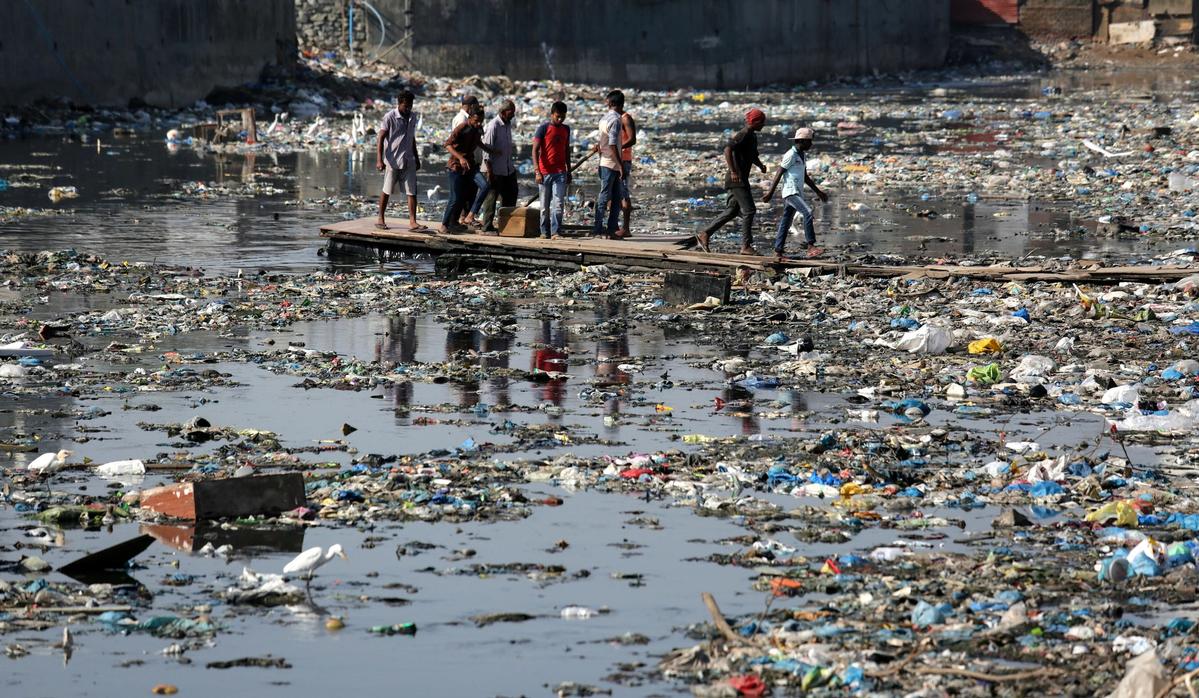 plastic waste and other litter with the help of a makeshift raft in Mumbai