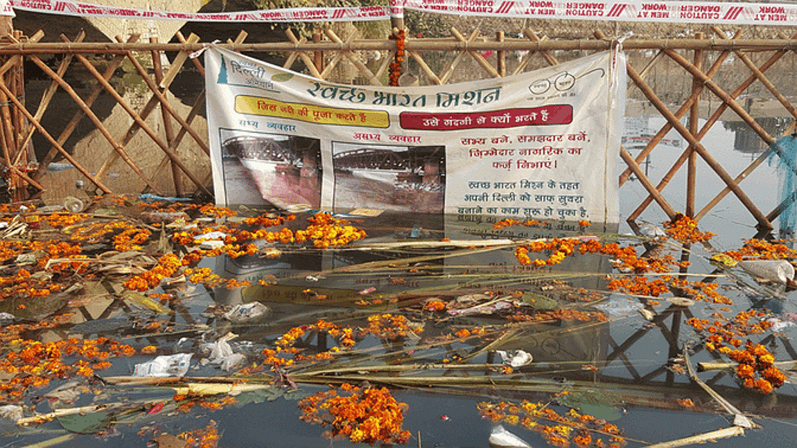 A Swachh Bharat Abhiyan banner was seen hanging on a fence in the canal amidst the waste