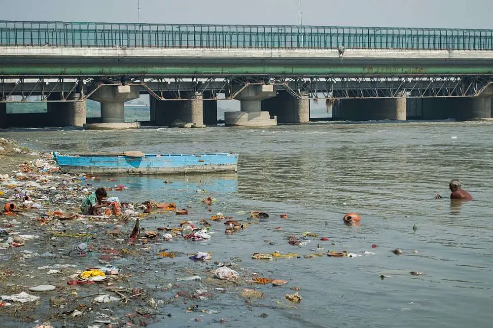 A child and his grandfather fish out valuable remains from religious offerings in the river