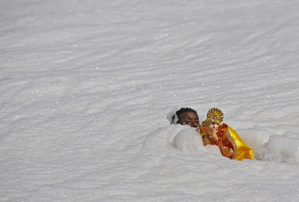 A devotee carries a statue of the Hindu god Ganesh through the polluted waters of the river Yamuna in New Delh