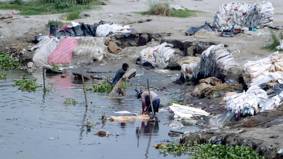 Indian washermen wash their clothes on the banks the polluted Yamuna river in New Delh