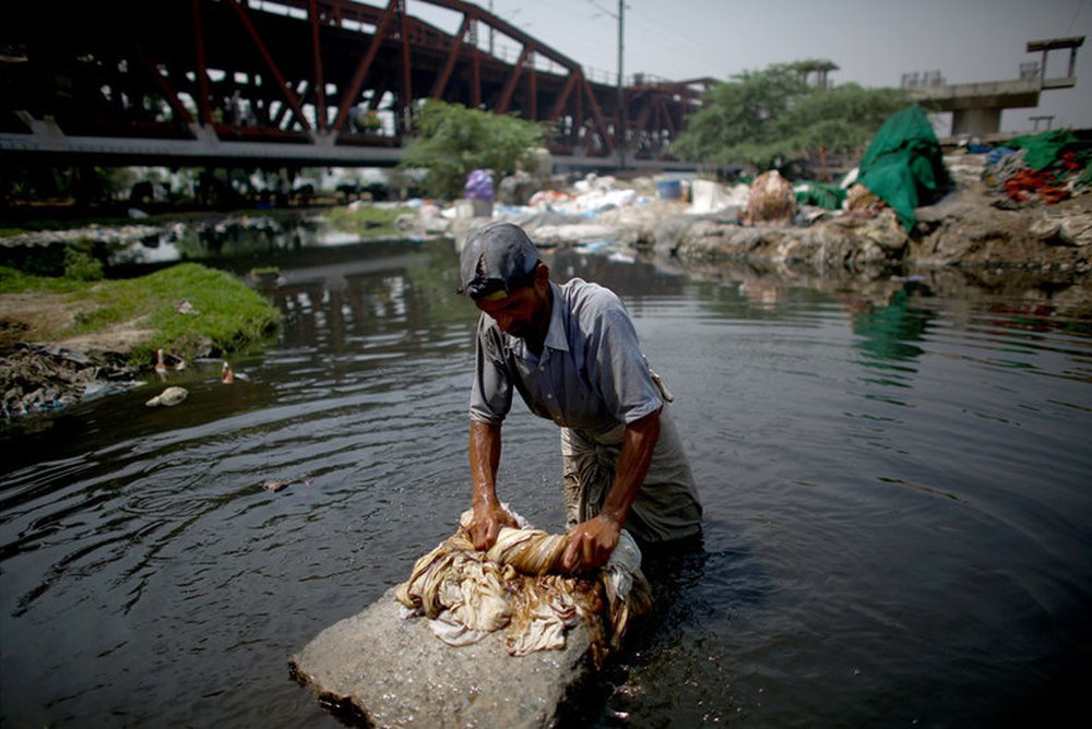Mohammad Zamir, 38, washes pieces of cloth on the banks of the Yamuna River
