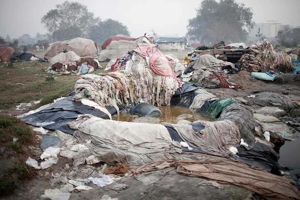 Piles of laundry from hotels lay in the mud along the Yamuna River