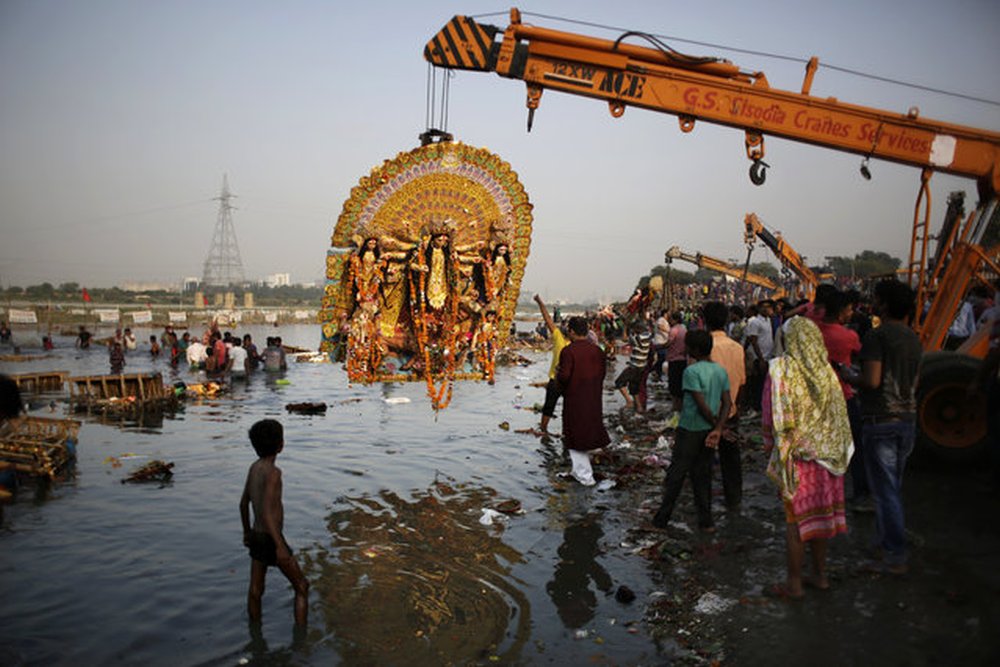 a giant Idol of Hindu goddess Durga suspends from a crane before it is immersed in the River Yamuna during Durga Puja festival in New Delhi, India