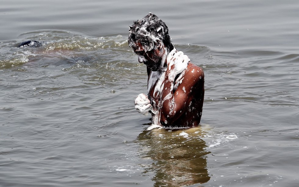 man bathes in the polluted waters of the river Yamuna in New Delhi
