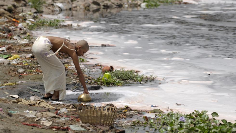 man fills water from the polluted river Yamuna in New Delhi