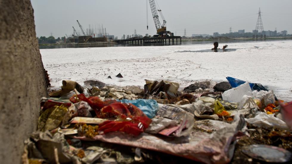 man searches for coins in the polluted waters of the Yamuna river in New Delhi
